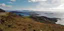 Brown hills sloping down to a blue bay with islands on the coast of County Kerry