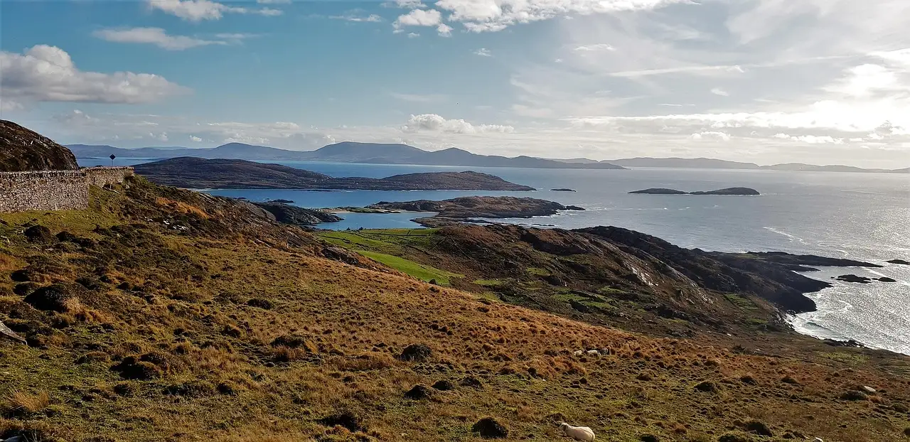 Brown hills sloping down to a blue bay with islands on the coast of County Kerry