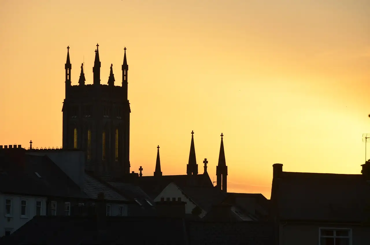 Kilkenny rooftops and church spires against an orange sunset sky