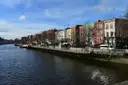 The River Liffey in Dublin in afternoon sun, with a row of quay buildings along the far bank