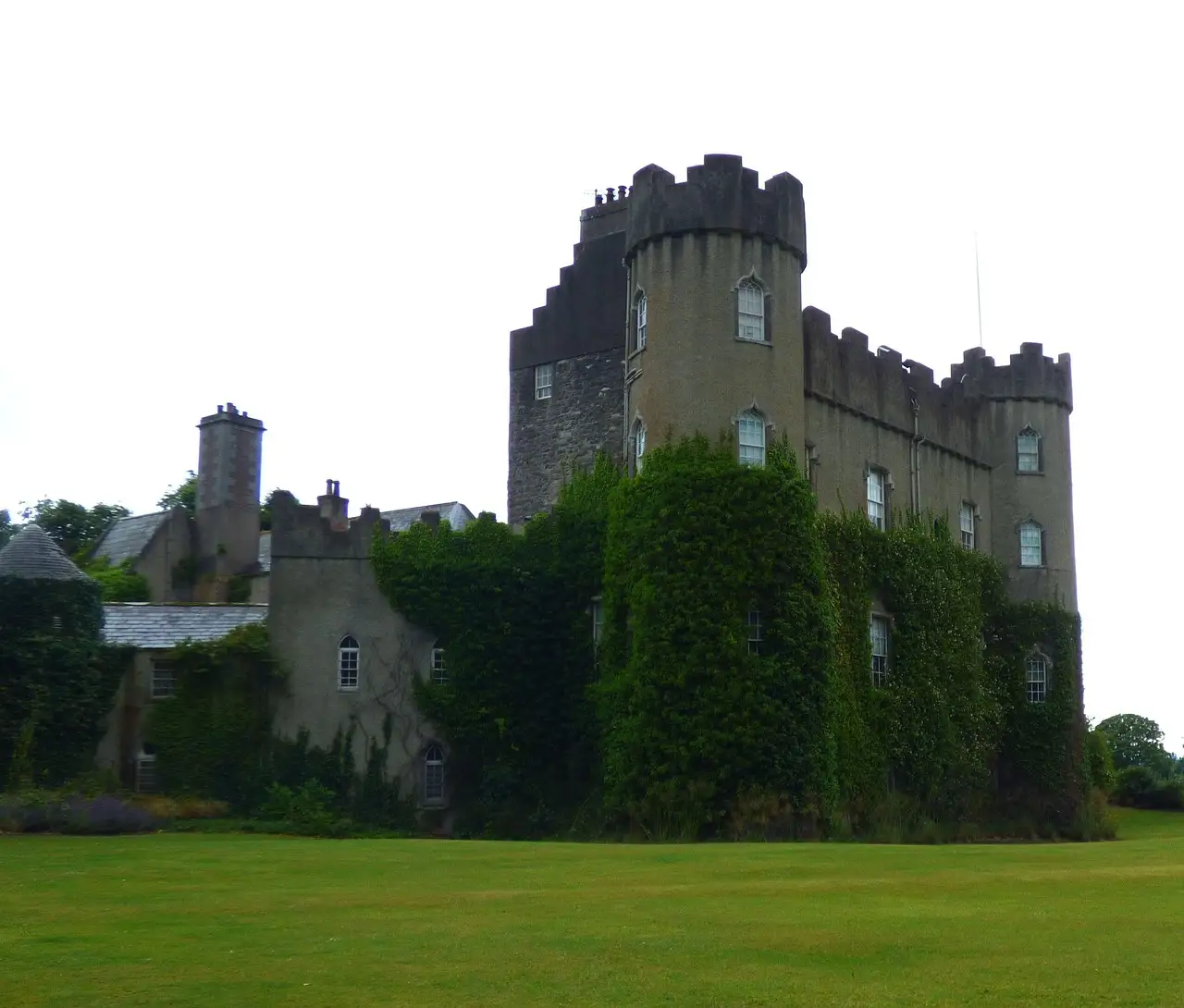 Malahide Castle, a grey stone castle with round towers, seen across the lawn