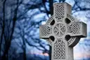 A carved Celtic high cross at dusk (a stand-in for the museum's early-Irish collections; no photo of the museum itself)