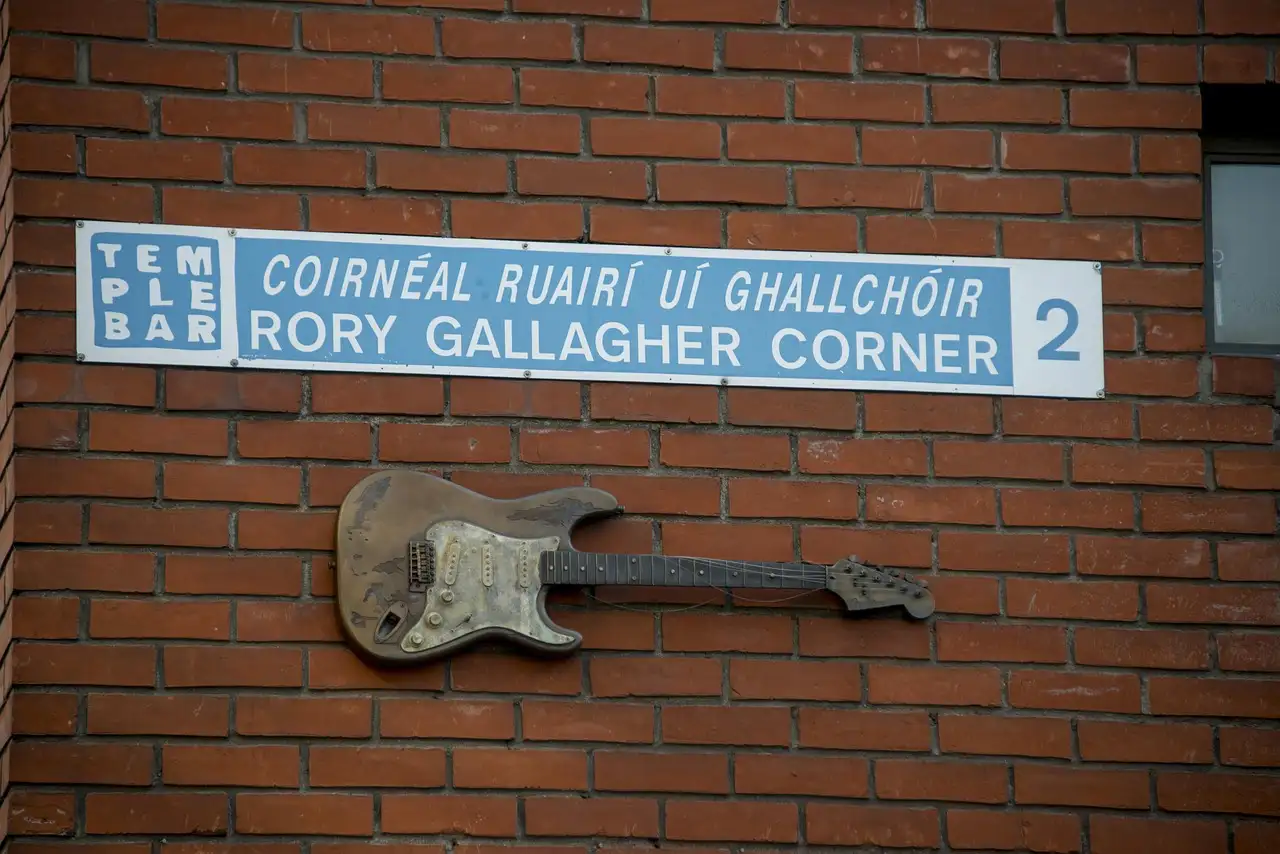 A Temple Bar street sign for Rory Gallagher Corner, with a guitar fixed to the brick wall