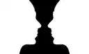 A black and white drawing that shows either a vase or two faces in profile