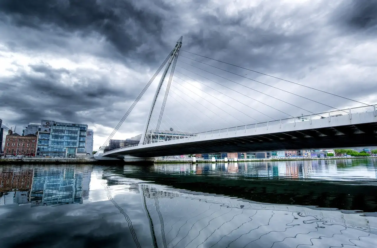 The white harp-shaped Samuel Beckett Bridge over the River Liffey under a stormy sky