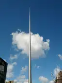 The tall steel Spire on O'Connell Street in Dublin against a blue sky with white clouds
