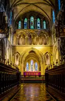 Inside St Patrick's Cathedral: carved wooden choir stalls, a tiled floor and tall stained glass windows above the altar