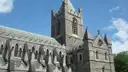 A grey stone church tower with pinnacles in Dublin, seen from below