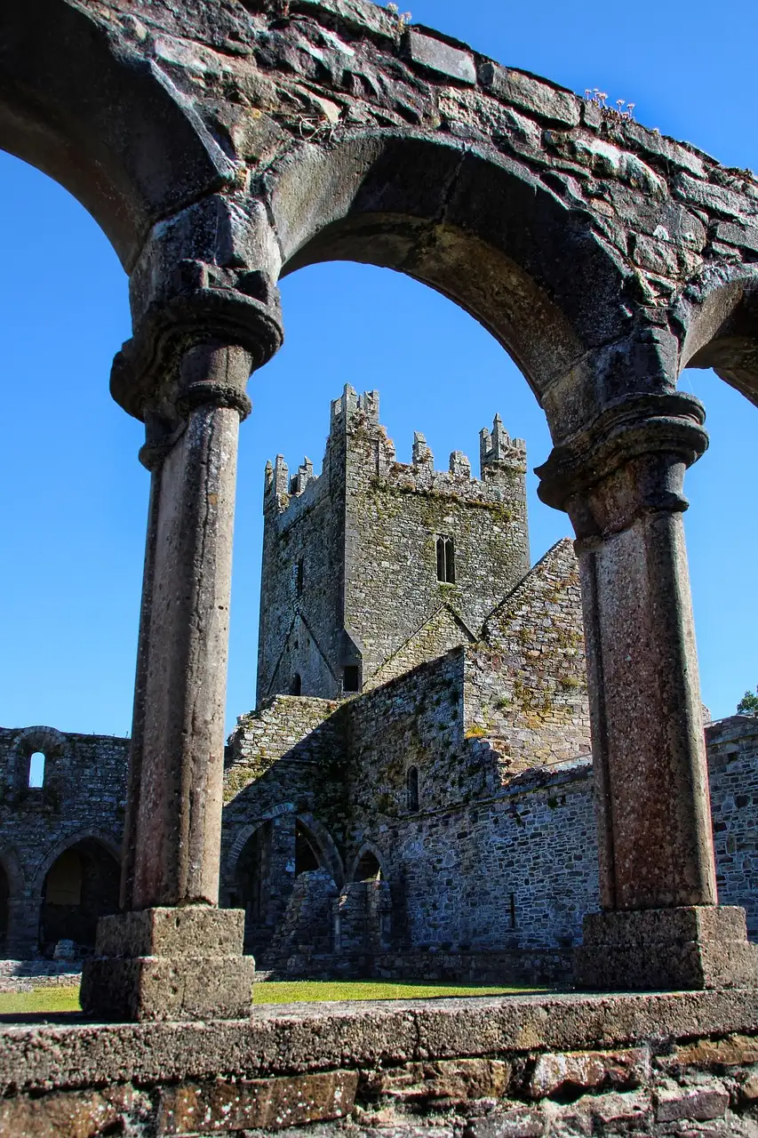 Ruined arches and tower of Jerpoint Abbey in County Kilkenny, seen through a stone arcade (a sight near the line's destination; no photo of the train itself)