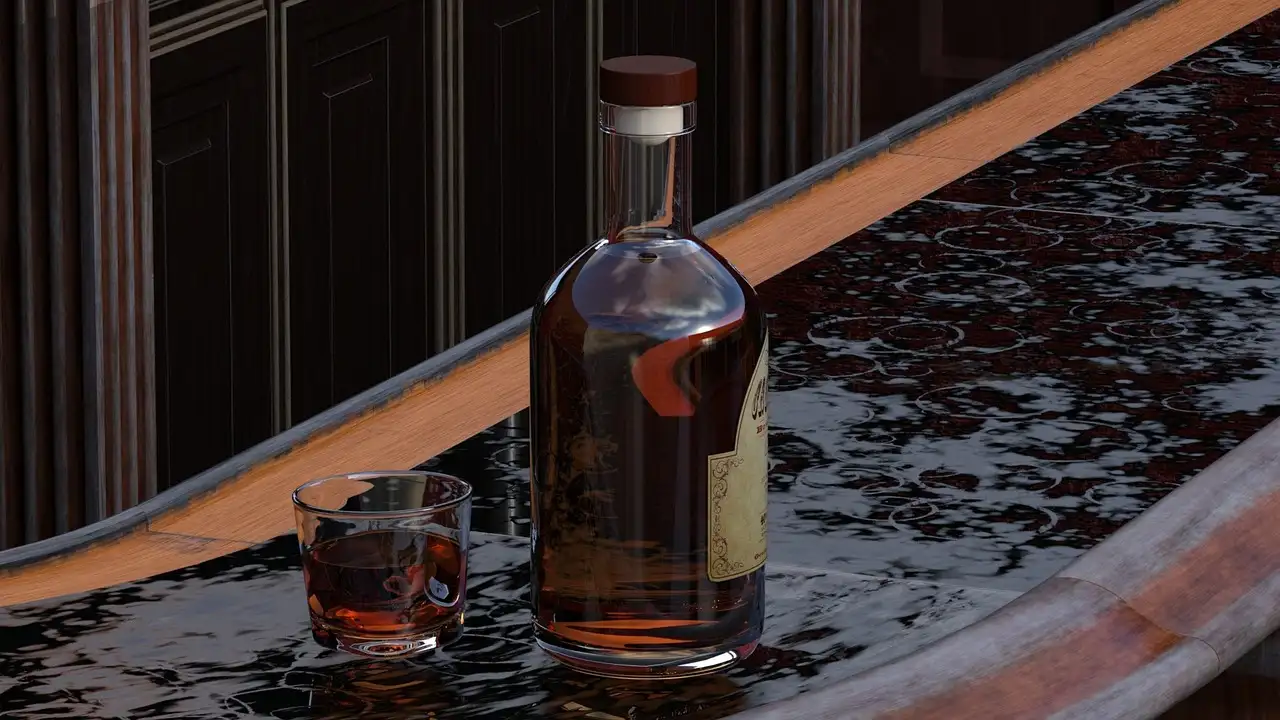 A bottle and a small glass of whiskey on a polished bar counter