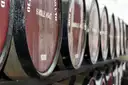 A row of dark wooden whiskey casks lying on their sides in a warehouse