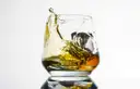 Whiskey swirling in a heavy glass tumbler on a white background
